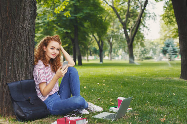 istock Happy young woman texting on smartphone in park 969543450