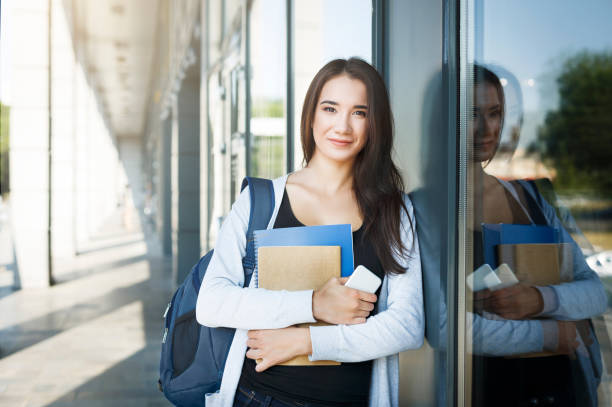 istock Young female IT student, with books, smartphone and backpack. Staying outside before lesson and smiling 969543522