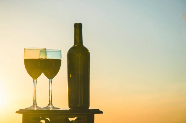 istock bottle of wine and two glasses on a sunset background 969555926
