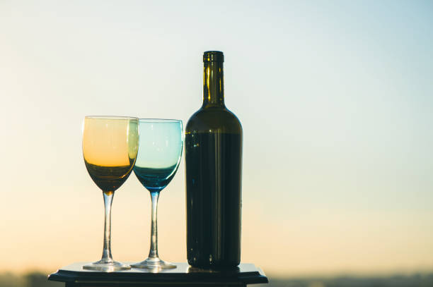istock bottle of wine and two glasses on a sunset background 969556332
