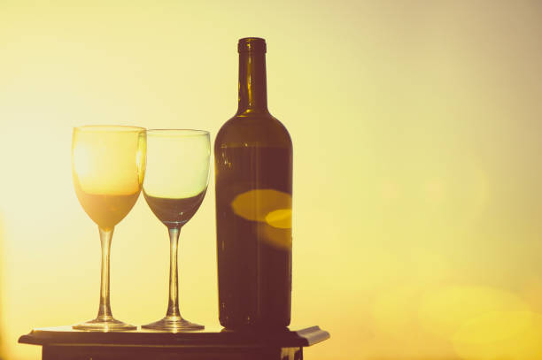 istock bottle of wine and two glasses on a sunset background 969556350