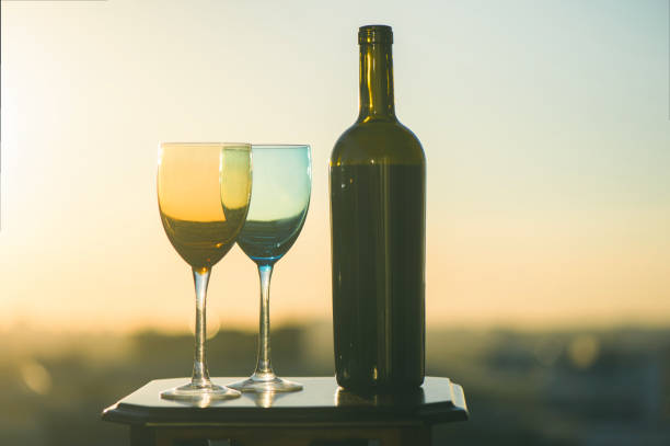 istock bottle of wine and two glasses on a sunset background 969556376
