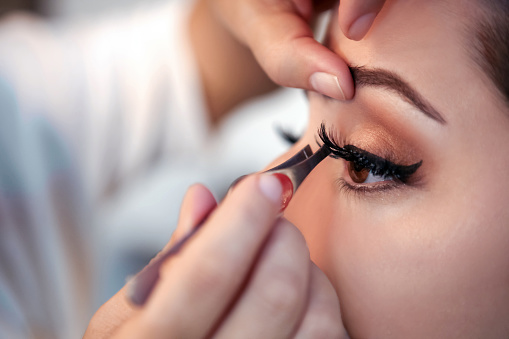 Makeup artist applying false eyelash