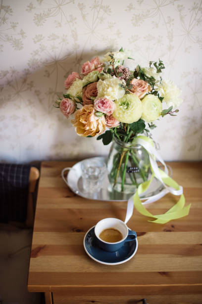 istock Delicious fresh morning espresso coffee in a blue ceramic cup with a saucer on the rustic wooden table along with blossoming flower bouquet with carnations, ranunculus, roses 969564398