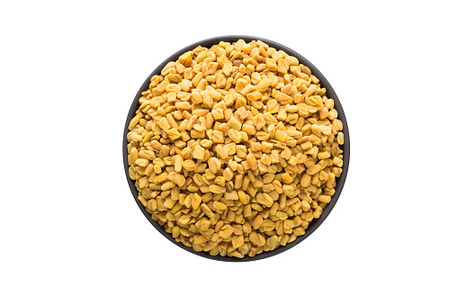 fenugreek seed in bowl, top view, isolated on a white background. organic spice