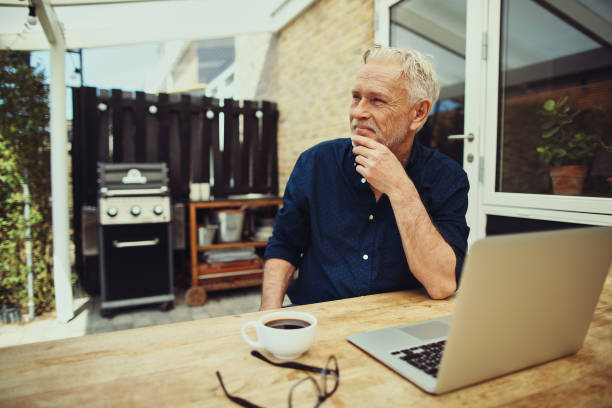 istock Content senior man sitting on his patio using a laptop 969571086