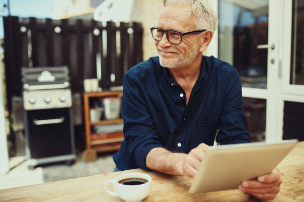 istock Senior man smiling and using a tablet on his patio 969572048