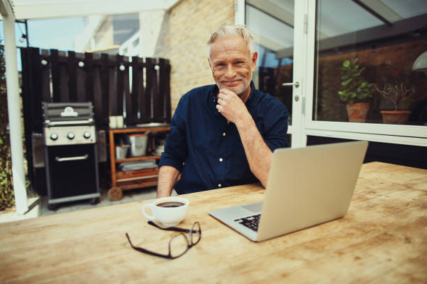 istock Smiling senior man relaxing on his patio using a laptop 969574526