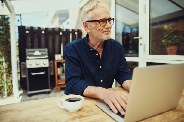 istock Smiling senior man working with a laptop on his patio 969574826