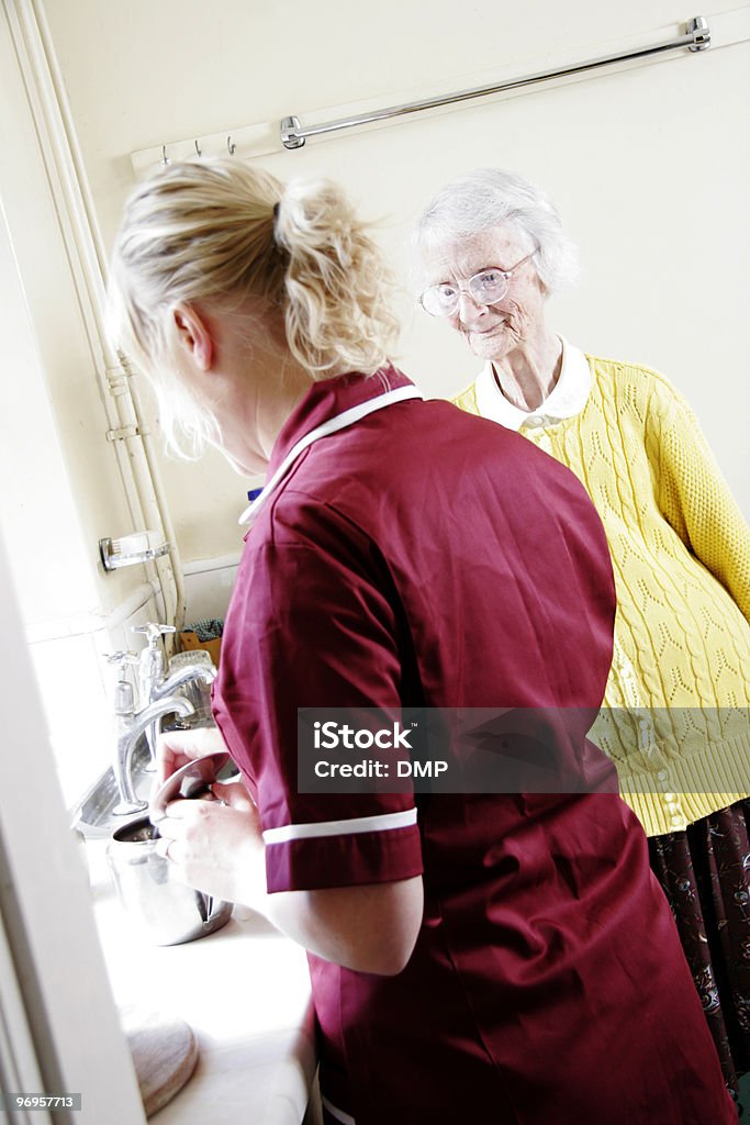 Jeune Infirmière faire du thé pour femme âgée de soin chez vous - Photo de Adulte libre de droits