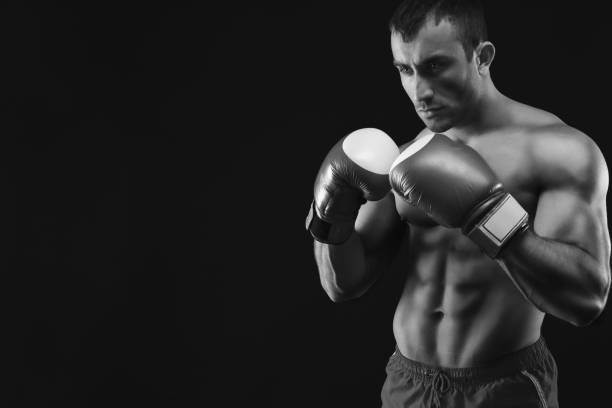 istock Muscular man in boxing gloves at black background 969579682