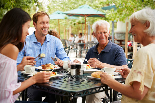 starsi rodzice z dorosłymi dziećmi korzystających z posiłku w kawiarni na świeżym powietrzu - 60s senior adult breakfast cheerful zdjęcia i obrazy z banku zdjęć