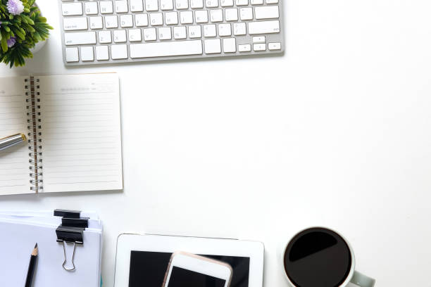 istock Office desk top view of workspace keyboard computer, coffee, notepad paper, pen, pencil and tablet smartphone on white table. 969582358