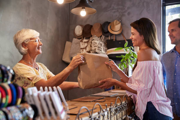 istock Store Owner Standing Behind Cash Desk Serving Customers 969583130