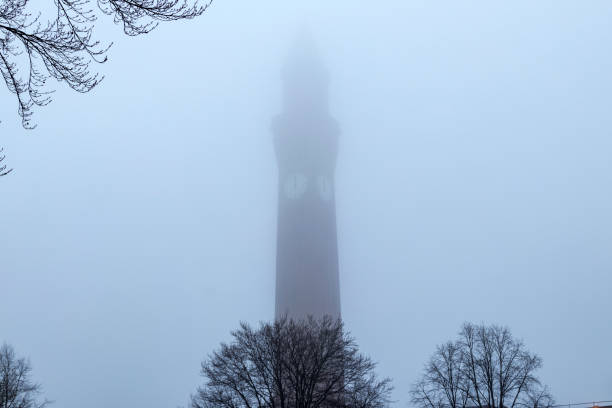 Tall clock tower vanishing into the mist stock photo