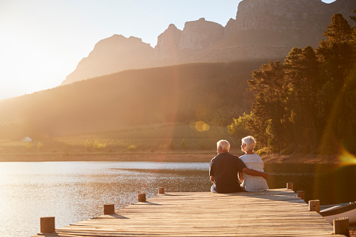 Romántica pareja Senior sentado en madera embarcadero lago photo