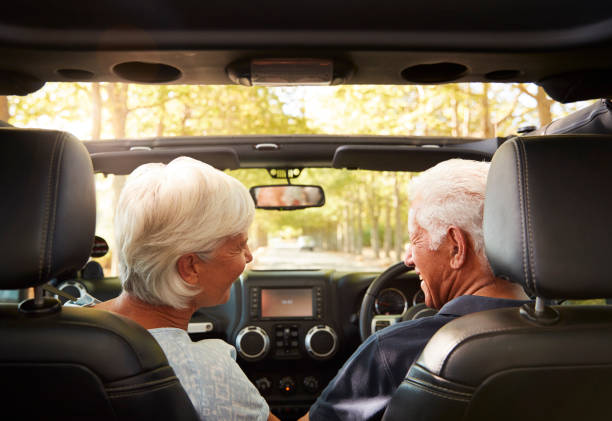 senior couple drive open top car on countryside road trip - driving senior adult car women zdjęcia i obrazy z banku zdjęć