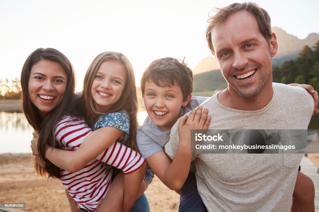 Ritratto di genitori che regala ai bambini un giro in piggyback in campagna - Foto stock royalty-free di Famiglia