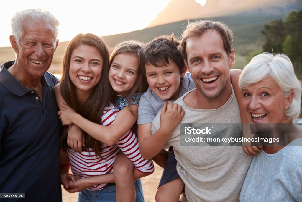 Ritratto di famiglia multigenerazionale in campagna a piedi sul lago - Foto stock royalty-free di Famiglia