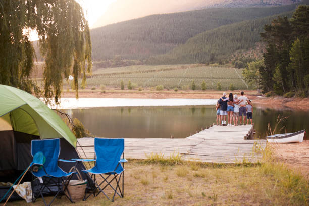 multi generation family on camping trip stand on jetty by lake - camping tent offspring 60s imagens e fotografias de stock