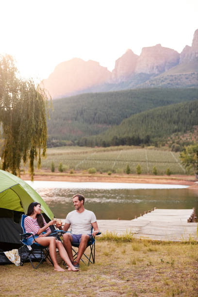 istock Couple Enjoying Camping Vacation By Lake Making A Toast 969586624