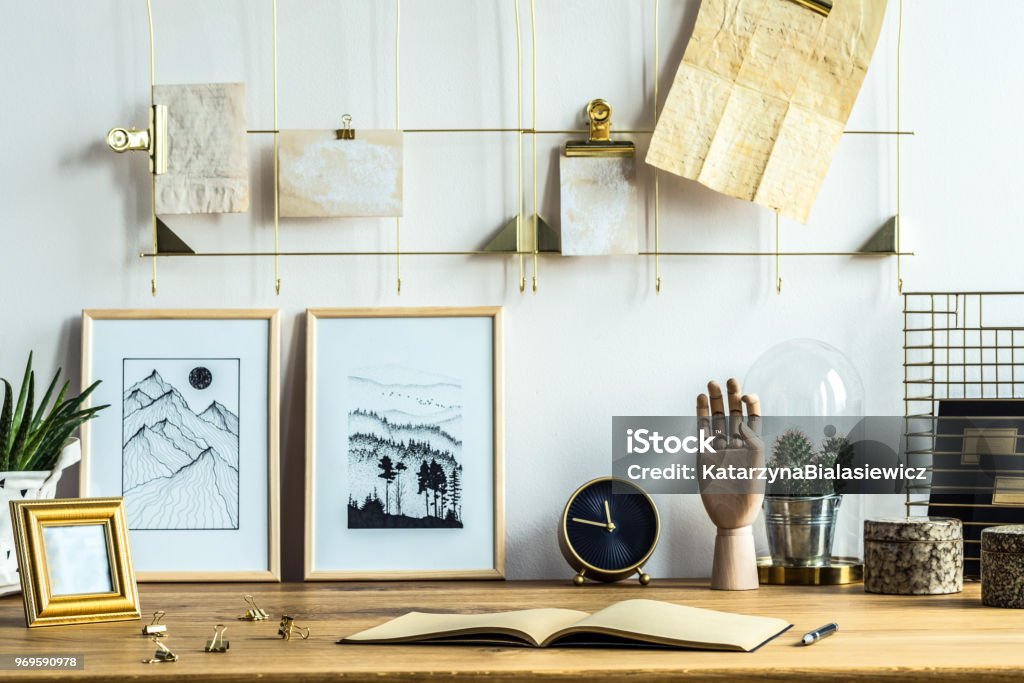 Home office interior with posters Notebook and posters on wooden desk in home office interior with gold clock Gold - Metal Stock Photo