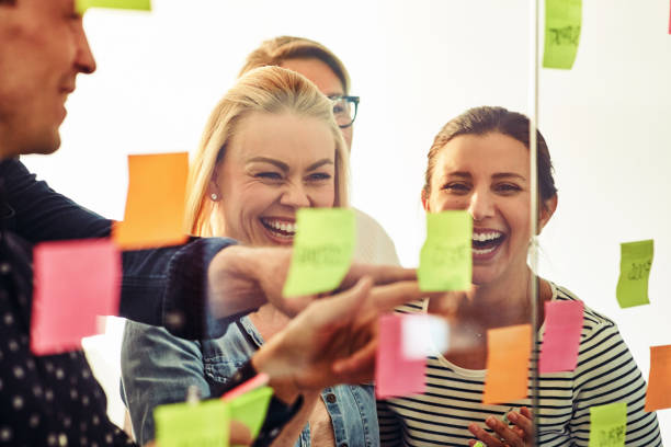istock Laughing businesspeople brainstorming with sticky notes on a glass wall 969595894