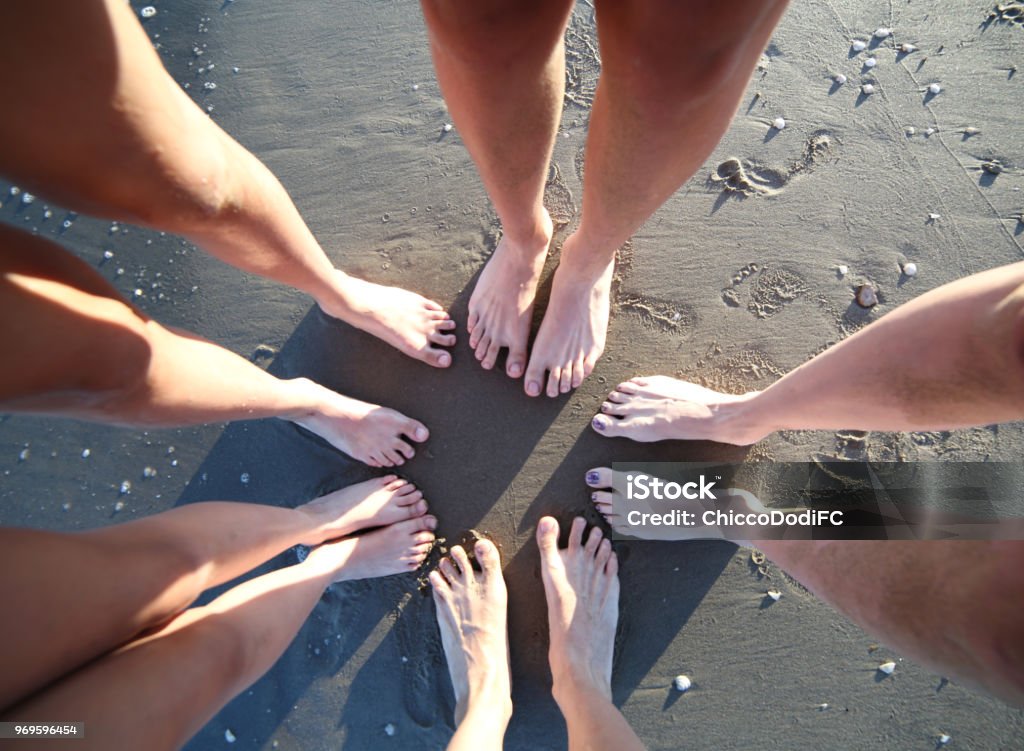 Barefoot feet of a family of five with legs on the sandy beach f Barefoot feet of a family of five person with long legs on the sandy beach forming a circle on the shore Circle Stock Photo