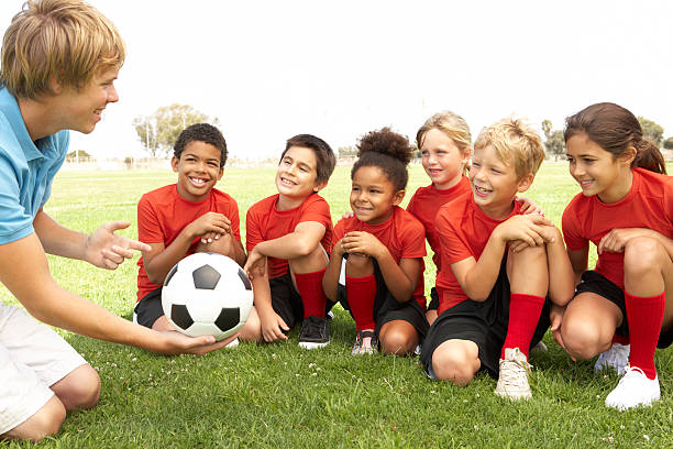 Young Boys And Girls In Football Team  With Coach Young Boys And Girls In Football Team Talking With Coach youth sports competition stock pictures, royalty-free photos & images