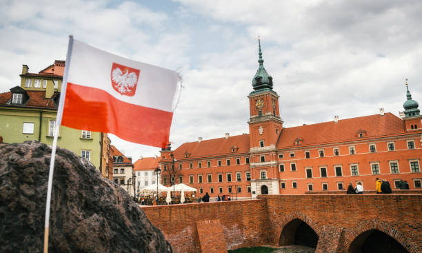 bandiera polacca davanti al castello reale. città vecchia di varsavia. - warsaw old town square foto e immagini stock