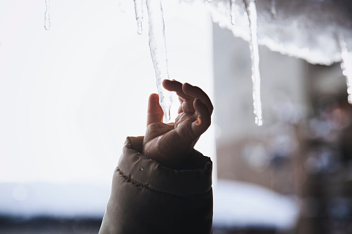 Hand of baby reaching for an icicle.