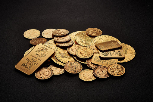 Yellow gold bars and coins isolated on black background.