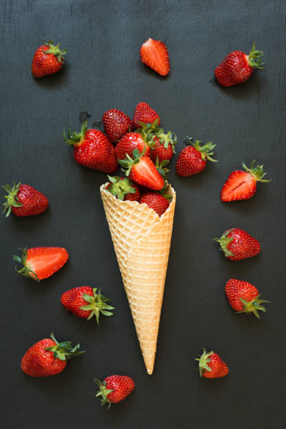 istock Ripe strawberry in ice cream cone on black. Close up. 969609644
