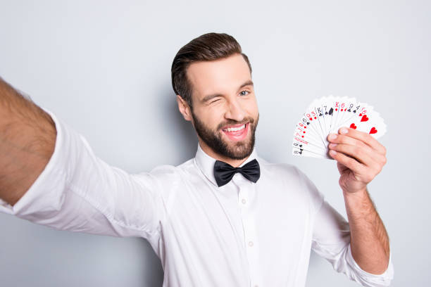 self portrait of playful flirting croupier shooting selfie on front camera winking with eye demostrate present set of cards, isolated on grey background, having leisure video-call - smiling casino human hand beautiful imagens e fotografias de stock