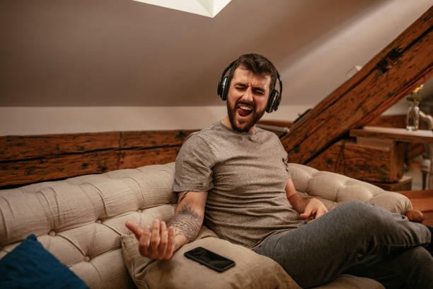 Rock'n'roll in his blood Young man listening to the music and playing imaginary guitar at home air guitar stock pictures, royalty-free photos & images