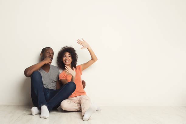 African-american couple hugging, sitting on floor Happy african-american family couple hugging and talking, sitting on floor in new apartment, dreaming about future, copy space, isolated dreaming stock pictures, royalty-free photos & images