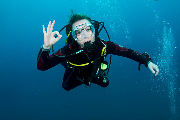 A DSLR Canon underwater photo of a 41-year-old Brazilian man free diving into clear turquoise water at Baía do Sancho in Fernando de Noronha, Pernambuco, Brazil.