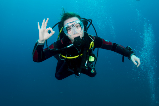 Water sports. Pretty scuba diver, attractive women, jumping to go scuba diving.  Sporting women. Beautiful blue sea in the background.