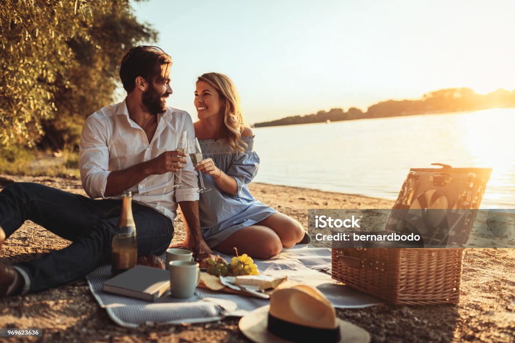Celebrating love A young couple cheering with champagne at the beach Picnic Stock Photo
