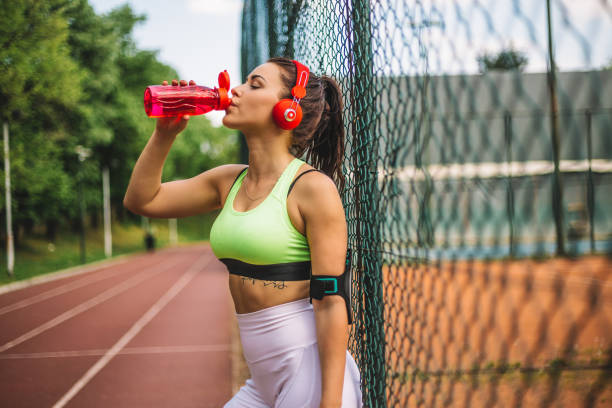 istock Woman runner is having a break and drinking water on running track 969628260