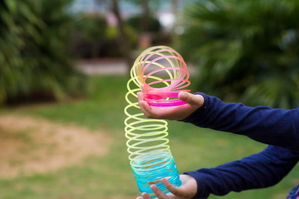Children playing with rainbow colored wire spiral toy on white background.