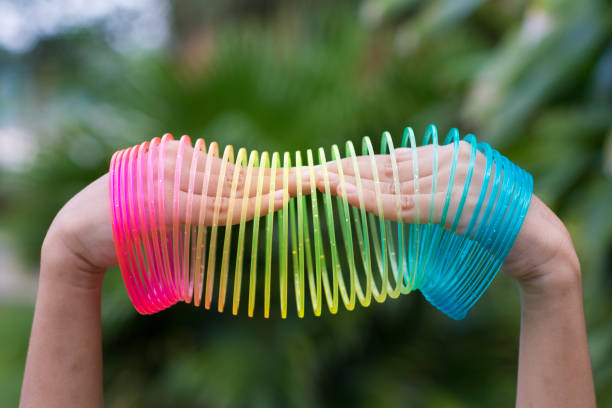 istock Children playing with rainbow colored wire spiral toy on white background. 969632970
