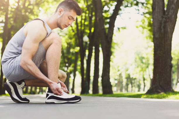 istock Muscular man tying shoelaces before running 969645132