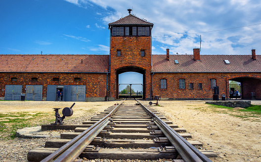 Main gate to nazi concentration camp of Auschwitz Birkenau with train rail, Poland on April 14, 2018.