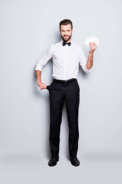 full size body portrait of stylish joyful magician with hairstyle having set of cards in hands and demonstrate empty pocket, isolated on grey background, making a focus, trick - smiling casino human hand beautiful imagens e fotografias de stock