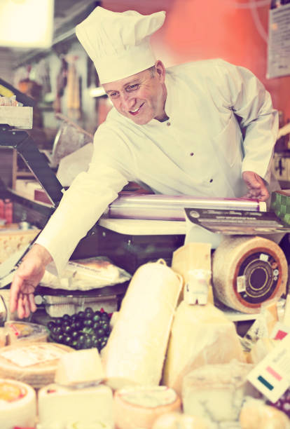 istock Man salesman selling soft and hard cheese in store 969649472