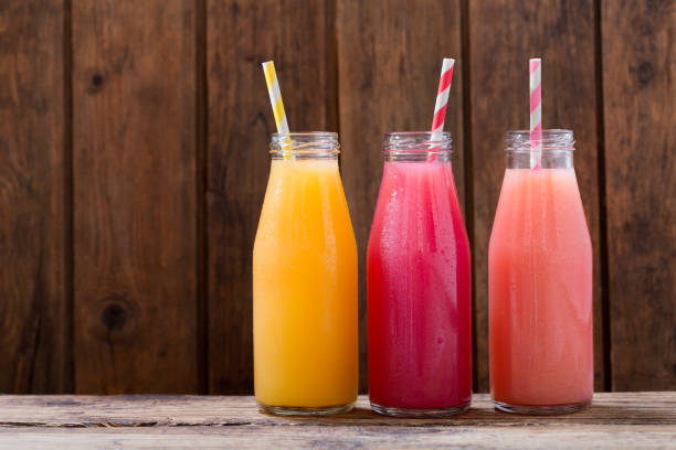 bebidas frias em um botlles na mesa de madeira - healthy eating fruit drink juice - fotografias e filmes do acervo