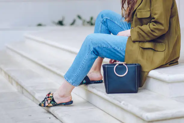 spring/summer outfit fashion details, young stylish woman wearing denim jeans and floral mules with a bow detail in front.