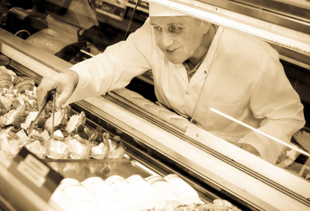 Mature man selling  tasty confectionery products Mature man selling  tasty confectionery products on counter of bakery old candy store stock pictures, royalty-free photos & images