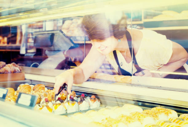 istock female baker offering fresh pastry 969677424